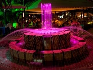 Un café al aire libre con una fuente que cambia de color. Armenia