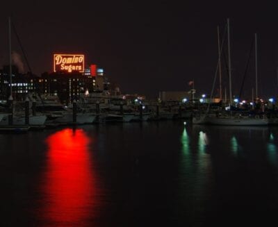 El símbolo de la clase trabajadora de Baltimore, la fábrica de azúcar de dominó en la noche a través del puerto... Baltimore Estados Unidos