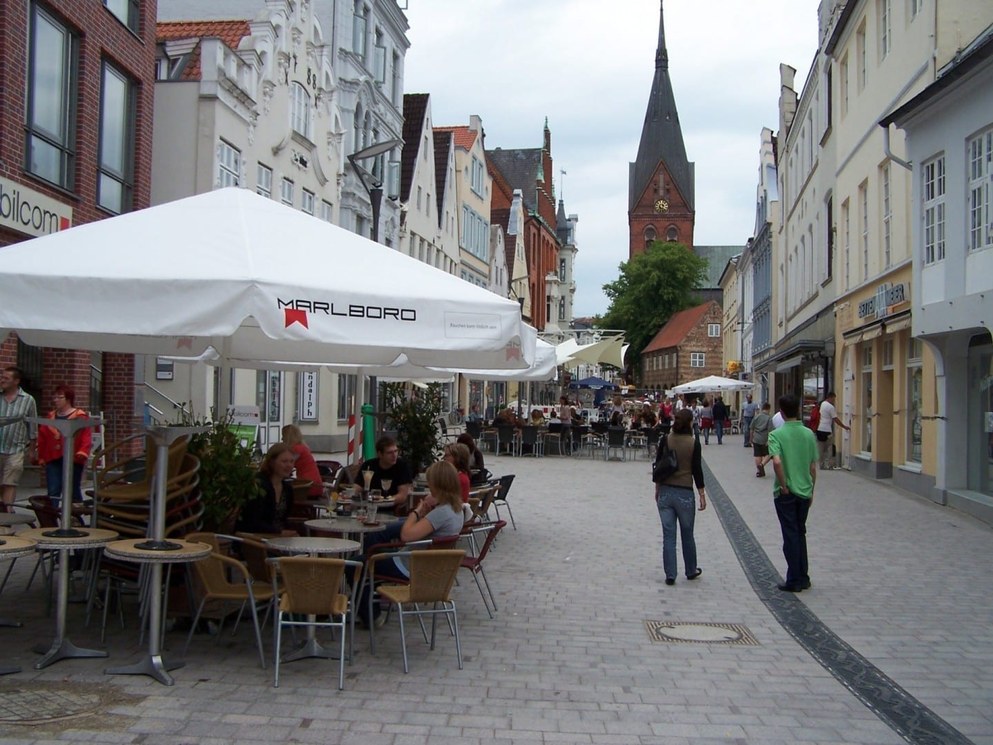 Ir de compras y comer en la calle peatonal Holm y Große Straße. En el fondo de la imagen está el San Marienchruch para ver. Flensburgo Alemania